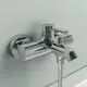 Chromene Wandarmatur von Ideal Standard mit zwei Griffen und einem Auslauf, montiert an grauer Wand, geeignet für Badewannen- oder Duschinstallationen.